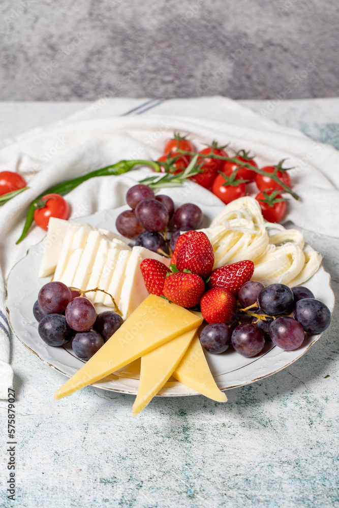 Cold cheese plate, cheese set platter. Strawberry, grape and cheese assortment on gray background Cold cheese plate, cheese set platter. Strawberry, grape and cheese assortment on gray background
