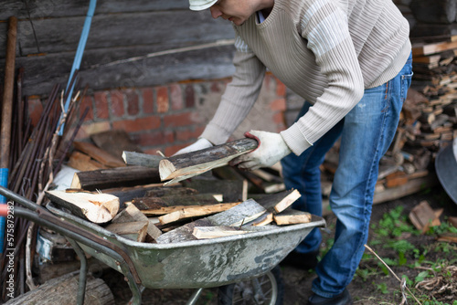 A man puts firewood from a cart into a firewood storage