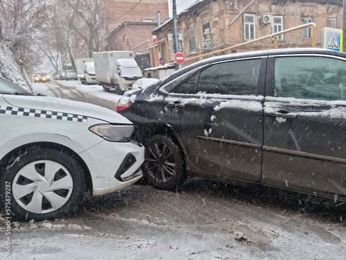 the collision of a white taxi and a black car due to ice. 