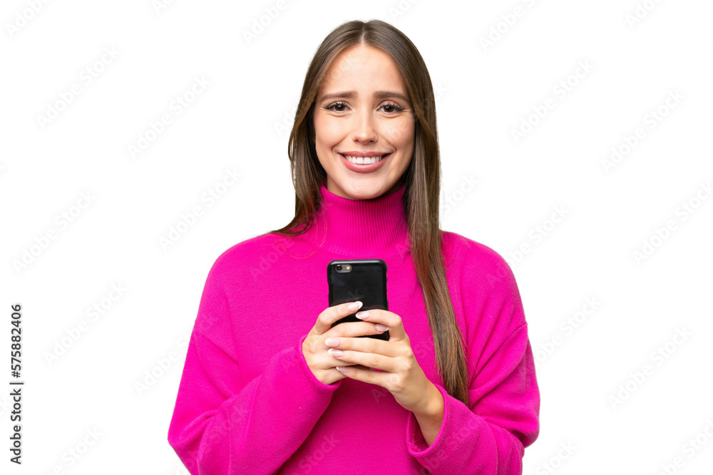 Young beautiful caucasian woman over isolated background looking at the camera and smiling while using the mobile Young beautiful caucasian woman over isolated background looking at the camera and smiling while using the mobile
