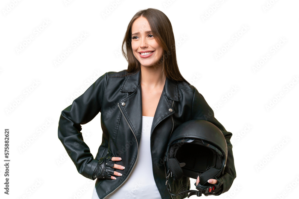 Young pretty caucasian woman with a motorcycle helmet over isolated background posing with arms at hip and smiling Young pretty caucasian woman with a motorcycle helmet over isolated background posing with arms at hip and smiling