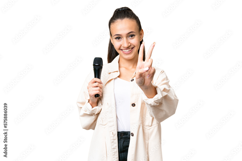 Young singer woman picking up a microphone over isolated chroma key background smiling and showing victory sign Young singer woman picking up a microphone over isolated chroma key background smiling and showing victory sign