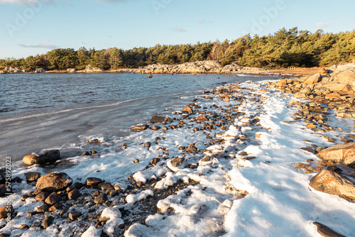 Costal winter panorama, glistering sunlight reflected in the ice and ocean, frozen beach, clear blue sky and green grass  on a beautiful clear winter day on the west-coast of Sweden photo