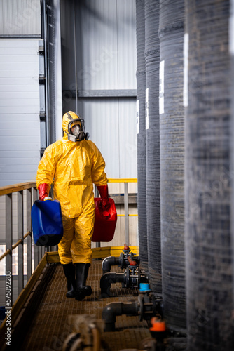 Chemicals worker standing by large acid reservoir inside factory.