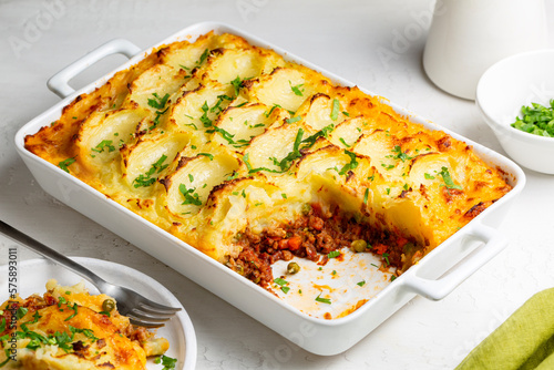 English Shepherd's pie, or cottage pie, or French version hachis Parmentier. Cooked minced beef meat with vegetables topped with mashed potato and baked.