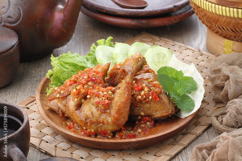 Ayam penyet  is Indonesian fried chicken dish consisting of fried chicken that is smashed with the pestle against mortar to make it softer, served with sambal, slices of cucumbers, fried tofu and temp photo