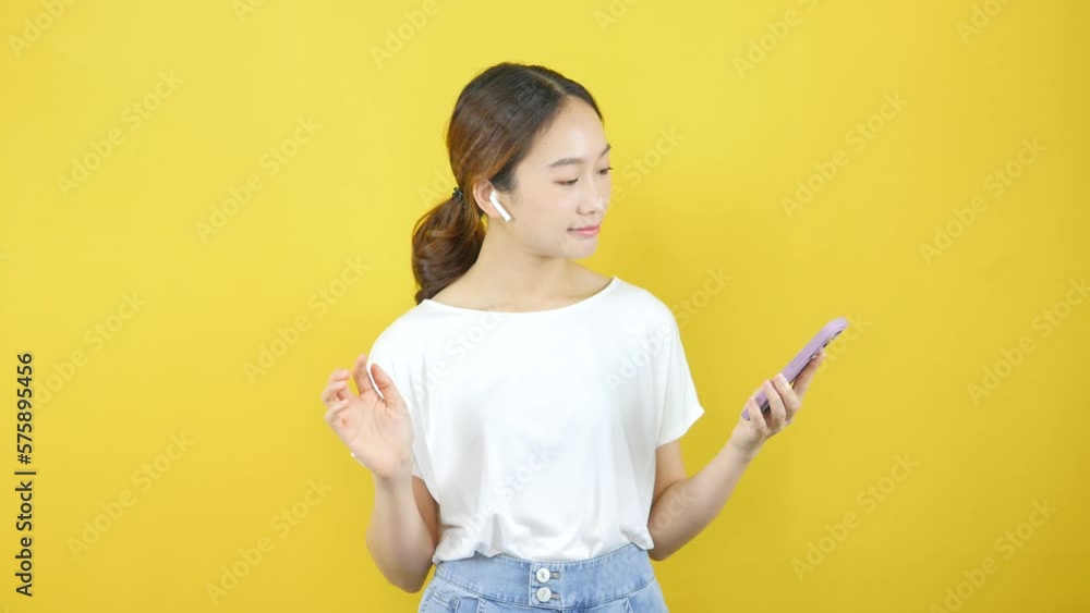Happy and cheerful Asian girls dancing and having fun, partying, moving rhythmic music and smiling on a yellow background. Happy and cheerful Asian girls dancing and having fun, partying, moving rhythmic music and smiling on a yellow background.