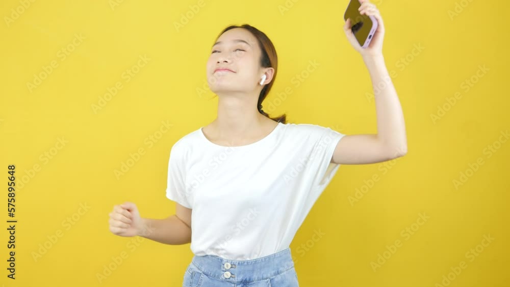Happy and cheerful Asian girls dancing and having fun, partying, moving rhythmic music and smiling on a yellow background. Happy and cheerful Asian girls dancing and having fun, partying, moving rhythmic music and smiling on a yellow background.