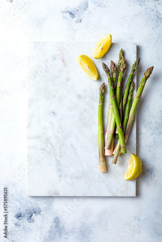 Bunch of fresh green asparagus on marble board. Green asparagus seasonal spring cooking. Overhead view, white background
