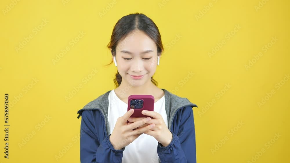 Asian woman in headphones smiling brightly and looking through video camera Asian woman in headphones smiling brightly and looking through video camera
