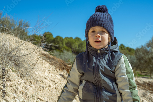 Child boy is hiking and exploring nature in the forest. Little boy travel in the sunny woodland.
