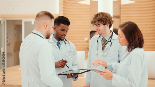 Multiracial doctors are consulting on a patient's case to find a treatment for patient at the hospital reception. A group of physicians is brainstorming and sharing treatment methods with each other.