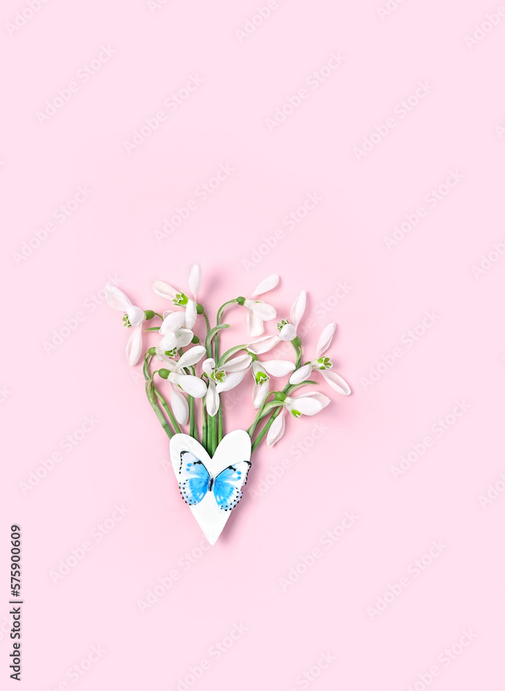 snowdrops flowers and paper heart with butterfly on abstract pink background. spring season. gentle nature image. hello spring, 8 march, Mother's day concept. flat lay. template for design
