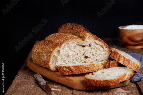 Rustic sourdough bread with cut slices on a wooden table. 