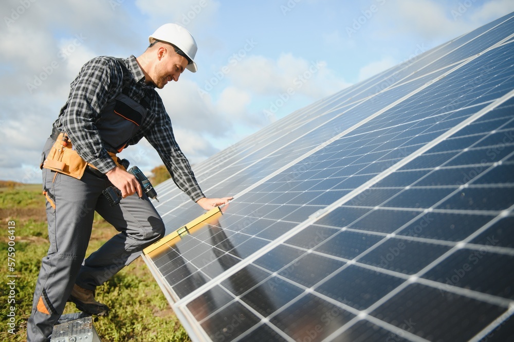 Male worker in uniform outdoors with solar batteries at sunny day. Male worker in uniform outdoors with solar batteries at sunny day.