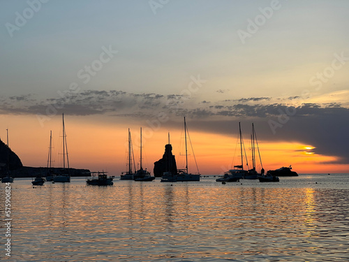 Fotografie Sailboats Silhouetted Against a Golden Mediterranean Sunset on the Coast of Ibiz