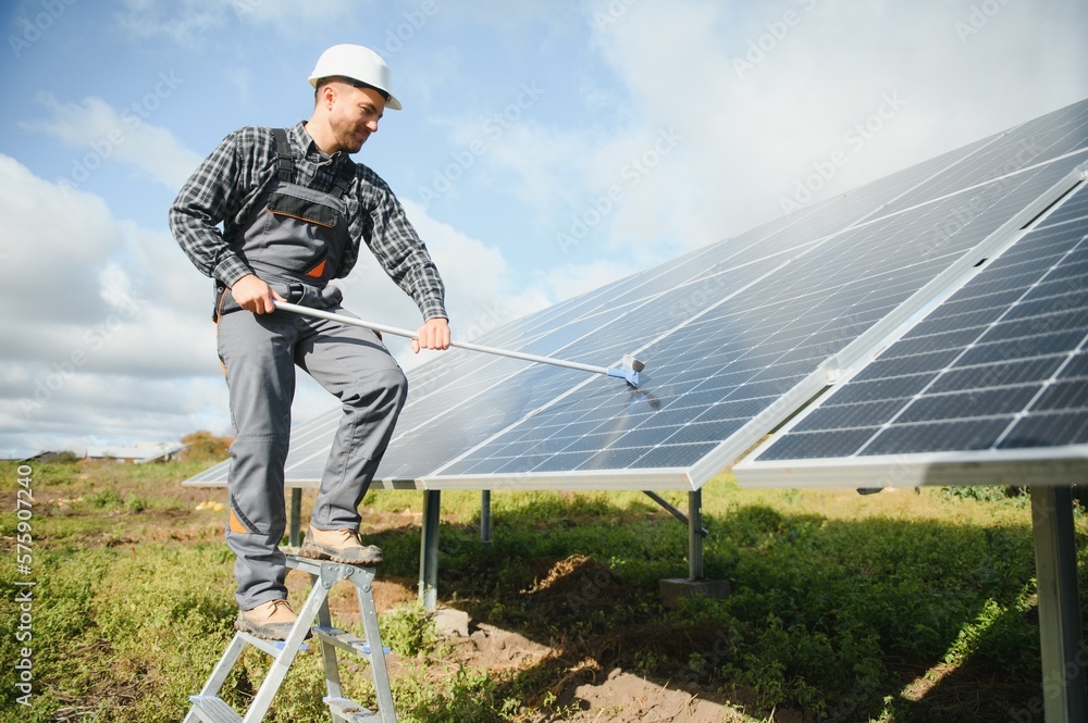 A worker cleaning dust and dirt form solar panels.