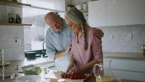 Happy senior couple cooking together at home.