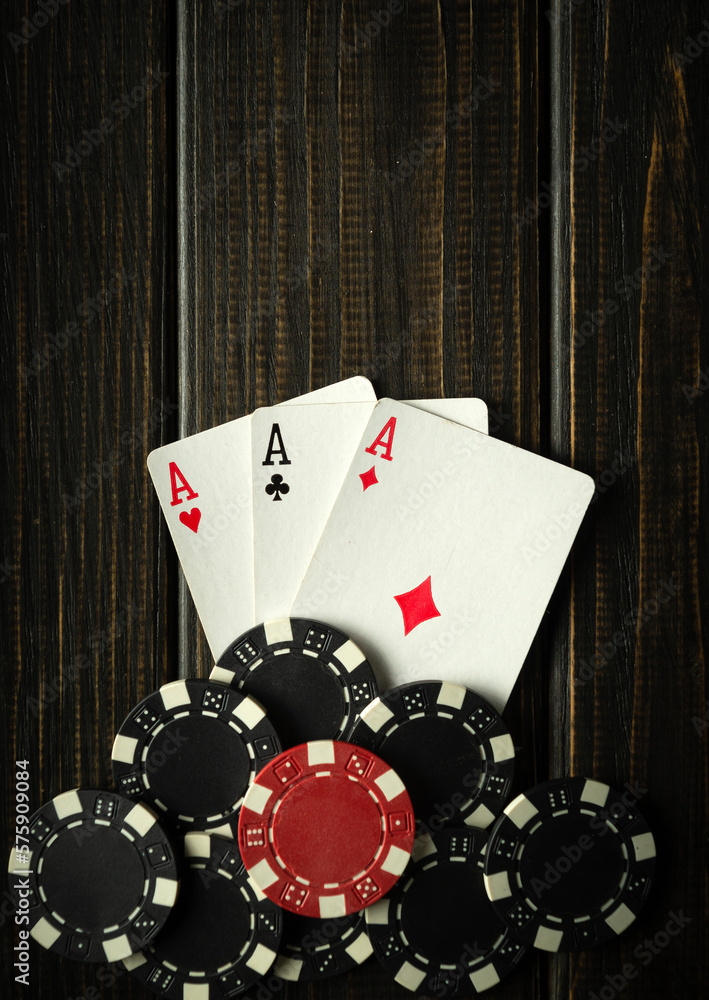 Obraz premium Playing cards with a winning combination of three of a kind or set on a black vintage table in a poker club. Winning in sports depends on luck