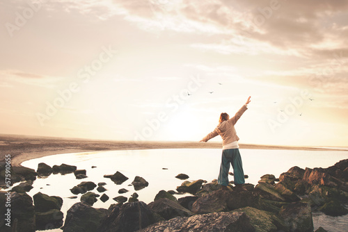 Photos woman with open arms meditates in front of a spectacular sea panorama