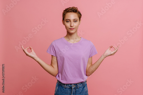Young beautiful calm woman showing meditation gesture looking at camera