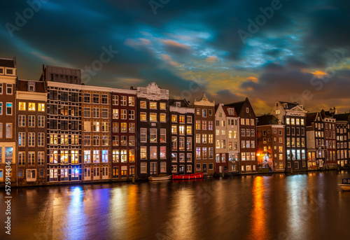 Typical houses on the Damrak at night, in Amsterdam, the Netherlands
