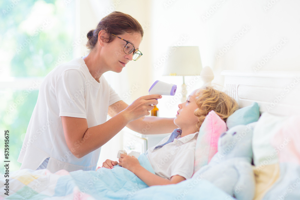 Fototapeta premium Sick child in bed. Mother checking on unwell kid.