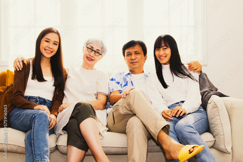 Perfect happy family : Portrait asian family Parents and sisters were together sitting on the sofa looking at the present camera as a souvenir spending time together warmly in the living room at home. Perfect happy family : Portrait asian family Parents and sisters were together sitting on the sofa looking at the present camera as a souvenir spending time together warmly in the living room at home.