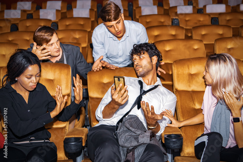Quadro em tela Concept Etiquette in the cinema Do not talk on the phone to disturb others : Man who is talking on the phone among moviegoers is annoying those around him who are upset for bad behavior