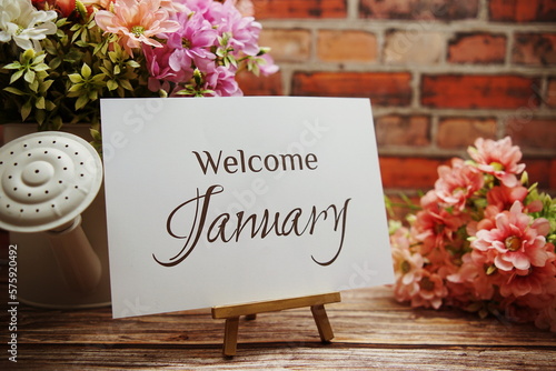 Welcome January text with flower bouquet decoration on wooden and old brick wall background