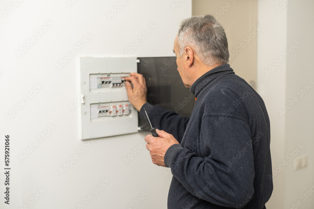 Elder man fixing an electric meter Elder man fixing an electric meter