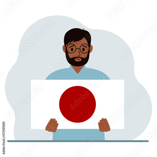 A man holds the flag of Japan in his hands. The concept of demonstration, national holiday or patriotism. Nationality.