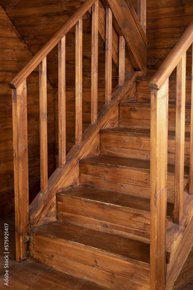 Wooden Stairway goes up. Country wooden house is spacious on two levels. Room with wooden stairway leading to second floor of modern flat. Modern staircase with wooden steps in flat. Wooden Stairway goes up. Country wooden house is spacious on two levels. Room with wooden stairway leading to second floor of modern flat. Modern staircase with wooden steps in flat.