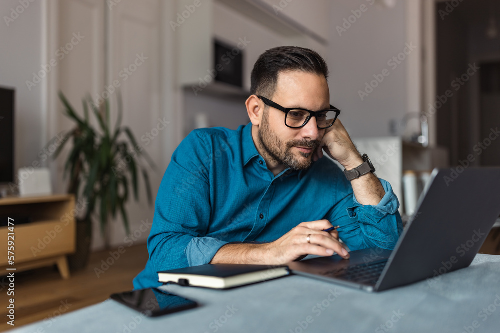 Focused male employer surfing the web over the laptop, sitting on the home floor. Focused male employer surfing the web over the laptop, sitting on the home floor.