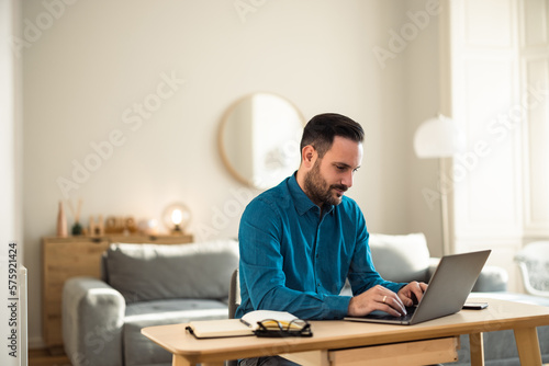 Busy male employee working over the laptop, sitting at the home office.