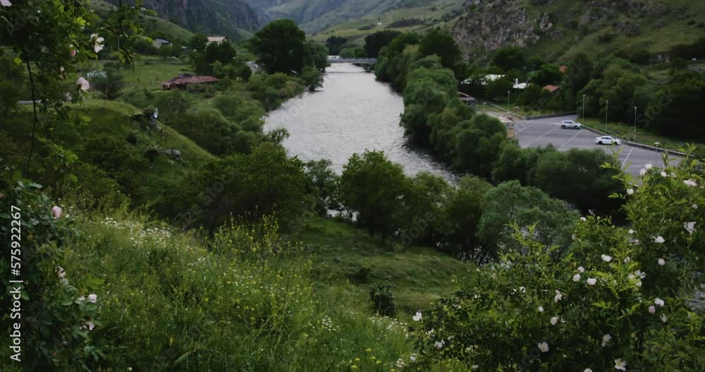 Blossoming meadow above meandering Vardzia river valley with village.