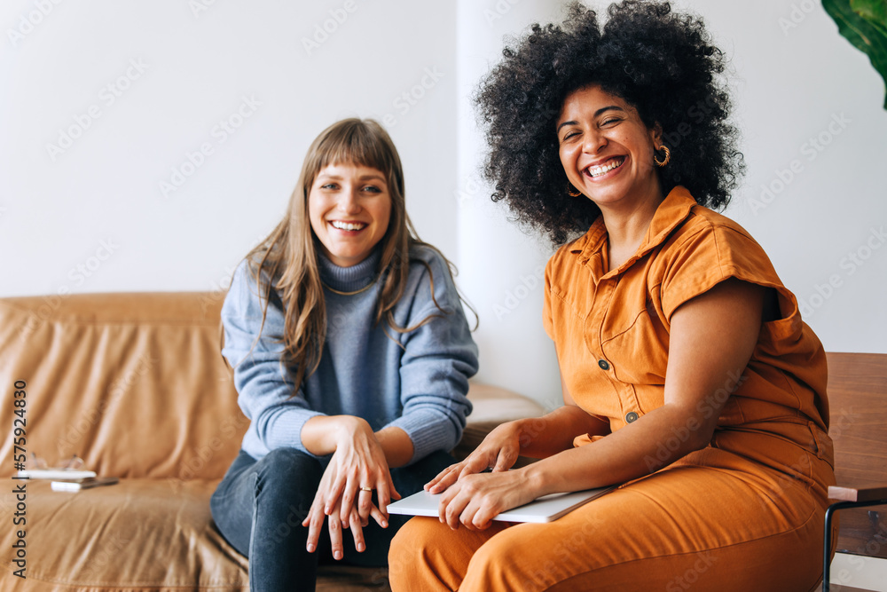 Two successful businesswomen smiling at the camera in a lobby Two successful businesswomen smiling at the camera in a lobby