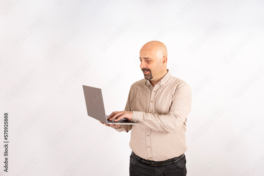 Working online, happy caucasian man holding laptop working online. Standing over isolated light gray background. Fingers on keyboard. Browsing internet, technology, office worker, remote job concept. Working online, happy caucasian man holding laptop working online. Standing over isolated light gray background. Fingers on keyboard. Browsing internet, technology, office worker, remote job concept.
