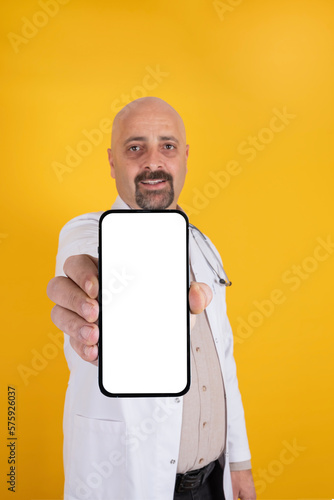 Recommending concept, portrait of male doctor showing empty white screen of smartphone. Vertical image of caucasian man hospital medical professional recommending concept idea with copy space.