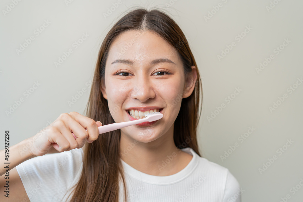 Close-up young woman brushing her teeth isolated on background Close-up young woman brushing her teeth isolated on background