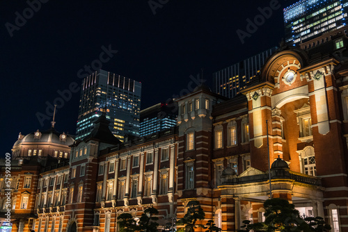 日本 東京都千代田区丸の内のライトアップされた赤レンガ作りの東京駅舎と高層ビル群の夜景