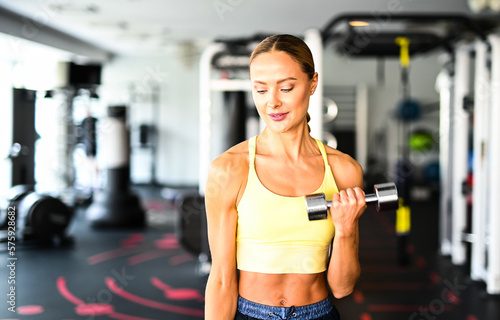 Beautiful young woman lifting dumbbells in a gym