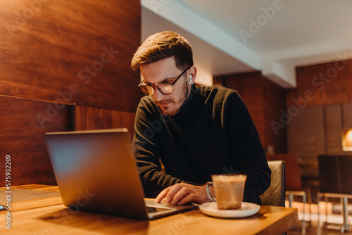 Happy young businessman working on a laptop in a cafe