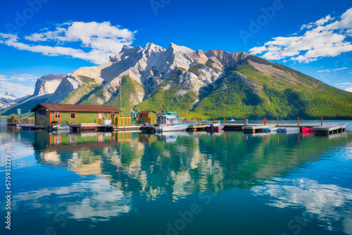 Mountain landscape at the day time. Boats near the pier. Lake and forest in a mountain valley. Natural landscape with a blue sky. Reflections on the surface of the lake.