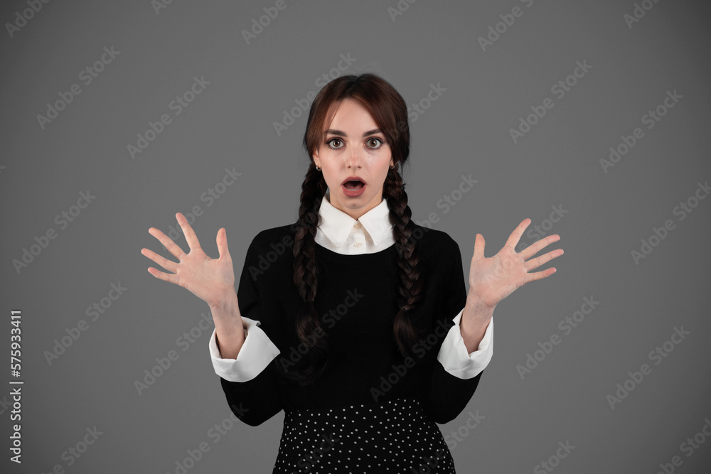 Shocked young girl student in gothic black clothes with pigtails with open mouth gesturing with hands Shocked young girl student in gothic black clothes with pigtails with open mouth gesturing with hands