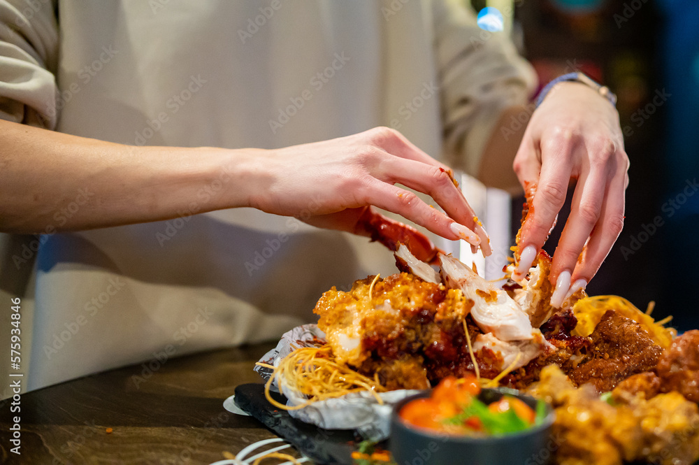 hungry woman hand holding and eatting fried chicken meat in pub