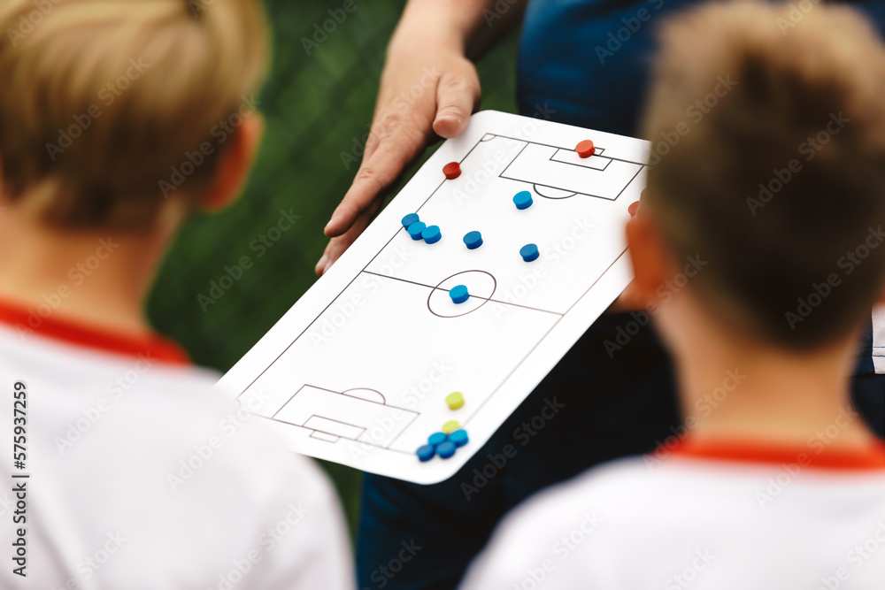 Soccer Coach Holding Tactics Board Football Tactics Board Strategy in Soccer. Coaching Kids Soccer. Football Team with Coach at the Stadium. Soccer Coach Holding Tactics Board Football Tactics Board Strategy in Soccer. Coaching Kids Soccer. Football Team with Coach at the Stadium.