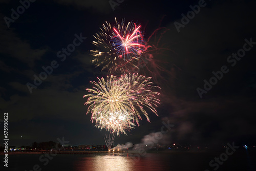 Aerial view of bright fireworks exploding with colorful lights over sea shore on US Independence day holiday