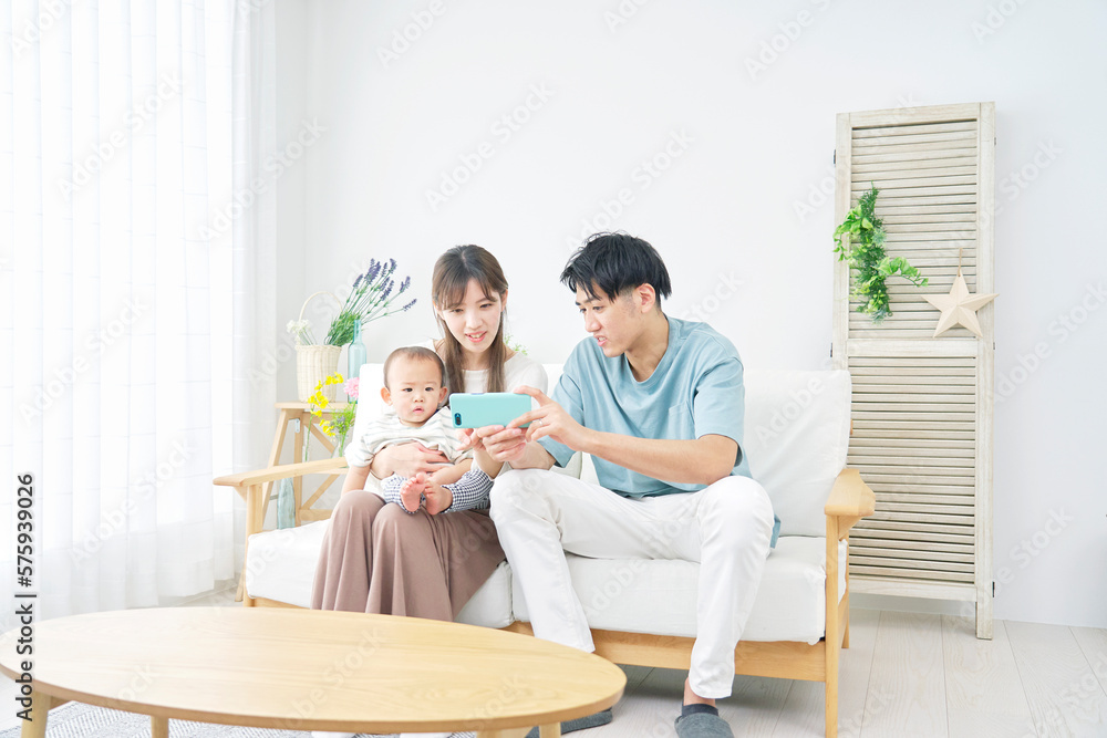 家で赤ちゃんとスマホを見る両親 家で赤ちゃんとスマホを見る両親
