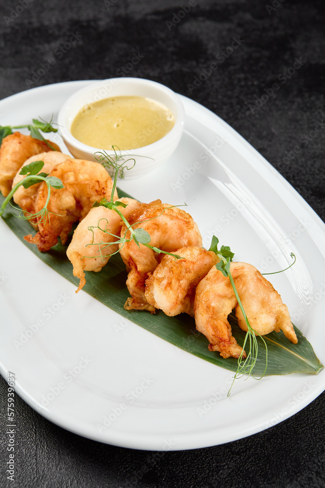 Appetizer of deep-fried shrimps with sauce. Crispy shrimps in tempura on black background. Fried prawns in asian style on dark concrete table. Asian prawns with sauce in minimal style. Appetizer of deep-fried shrimps with sauce. Crispy shrimps in tempura on black background. Fried prawns in asian style on dark concrete table. Asian prawns with sauce in minimal style.